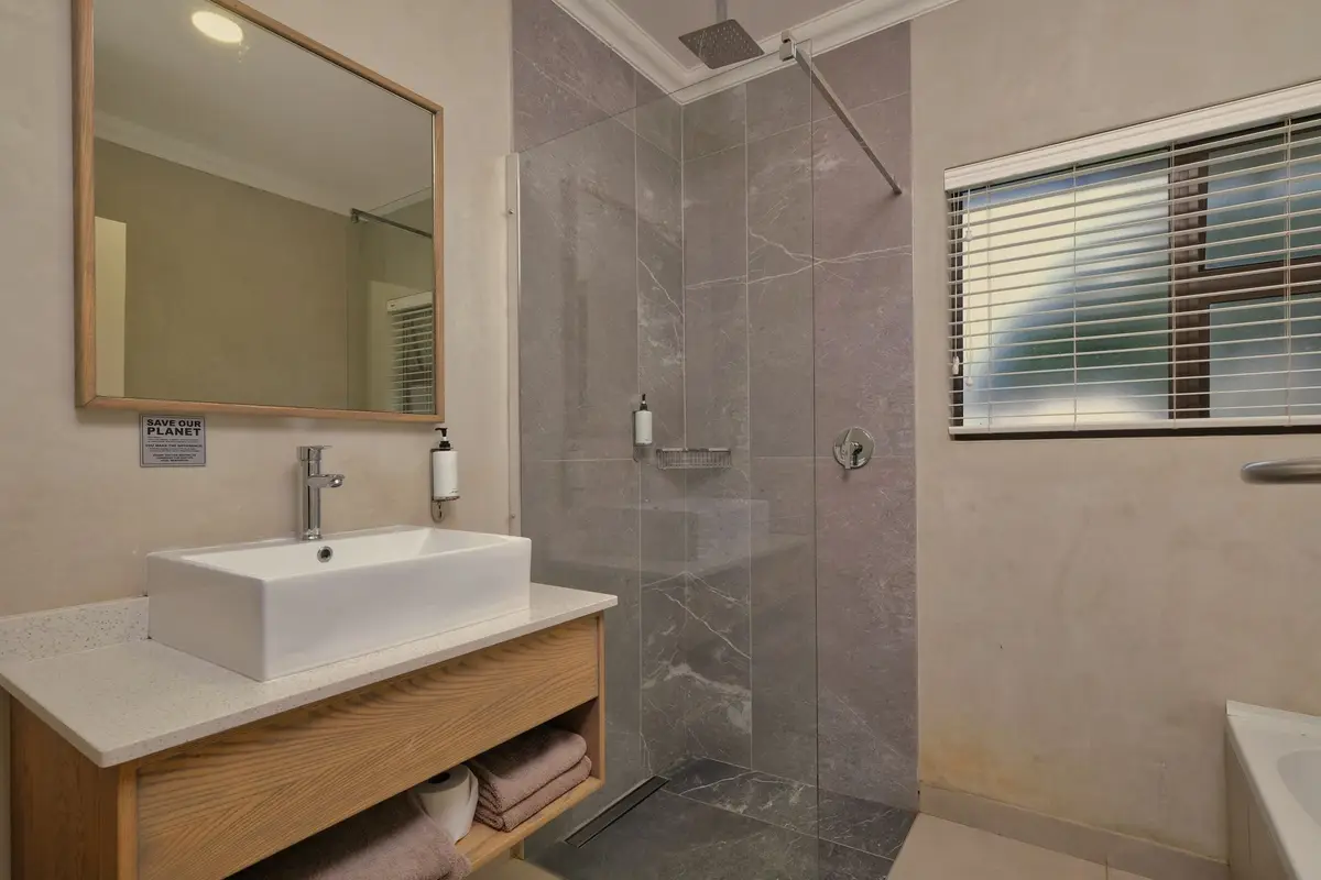 Modern bathroom with a glass walk-in shower, floating wood vanity and gray tile